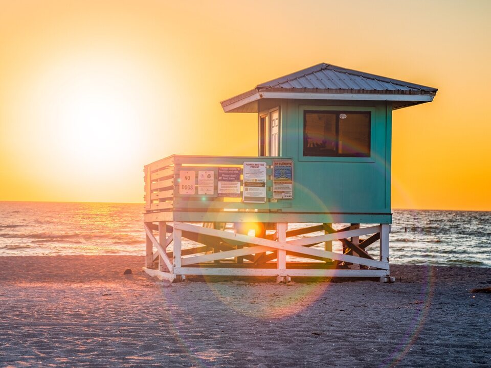 A turquoise lifeguard tower at sunset on a Venice, Florida beach